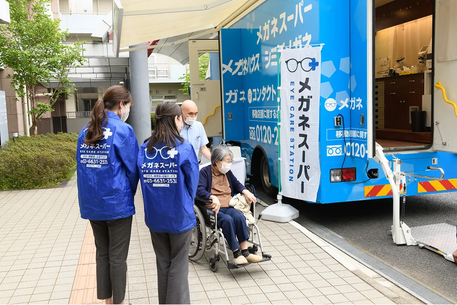 出張訪問サービスの車両の前で車いすの利用者に付き添うスタッフ