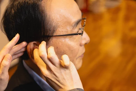 耳に手を添えて音を聞く男性