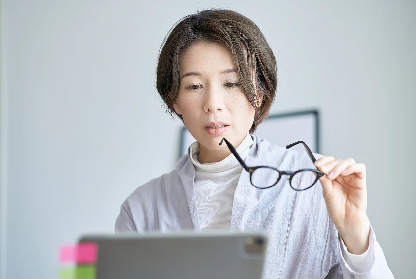 近くを見るときにメガネを手に持つ女性