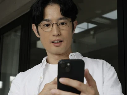 スマートフォンの画面を見つめるメガネの男性