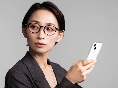 スマートフォンを持って横を向くメガネの女性