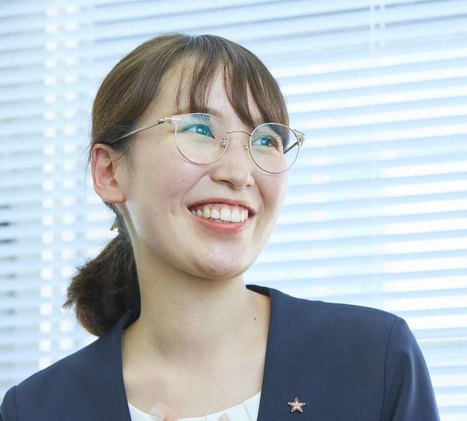 インタビューに答える、メガネをかけて笑顔の女性(開発プロジェクトチーム)
