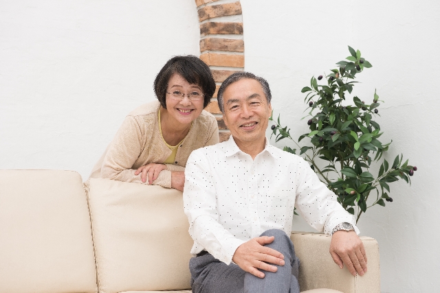 ソファでくつろぐ笑顔の高齢の夫婦